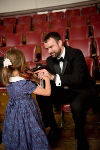 Melrose Schools Orchestra Director Luke Miller, seen here assisting a young student with the violin, has been named the state's Orchestra Director of the Year. (Courtesy Photo/Melrose Symphony Orchestra)