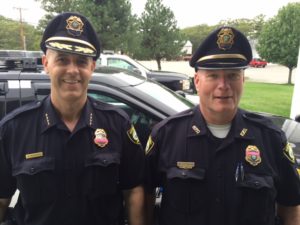 Left-to-right: Officer NAME and Officer NAME donning pink bands on their badges in support of MASS C.O.P.'s Breast Cancer Awareness Campaign.