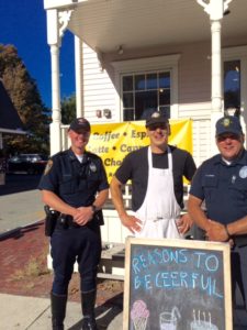 Officer Ron Holsinger (left) and Officer Robert Capone (right) stand outside of Reasons to be Cheerful with owner, Wade Rubinstein (center) who donated free scoops of ice cream to the Good Behavior Citation program.